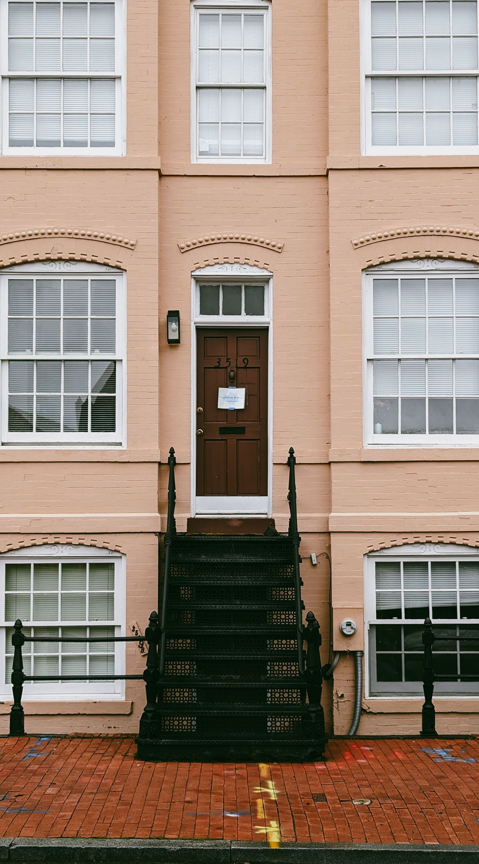 Beige building facade featuring an elegant entrance with steps and multiple windows, creating a classic urban view.
